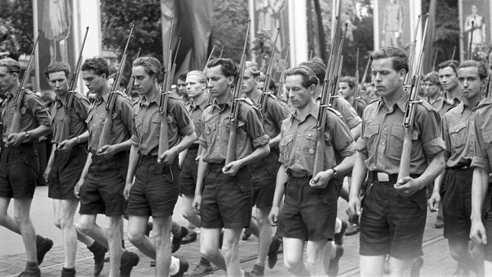 Junge Männer der Freien Deutschen Jugend (FDJ) marschieren mit Gewehren (1952)