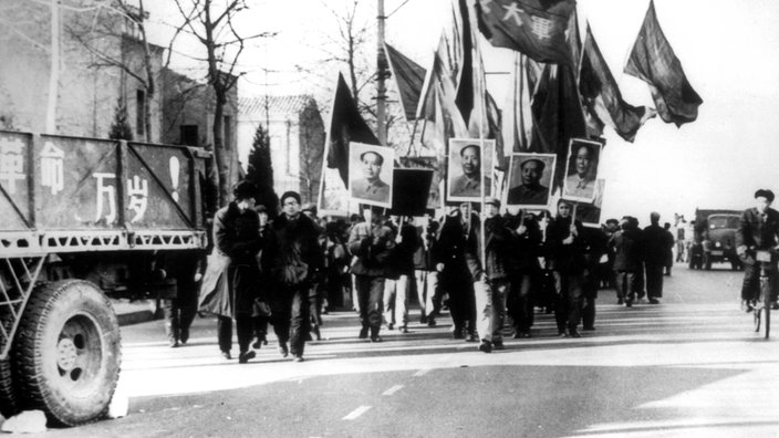 Rotgardisten schwenken Fahnen und marschieren durch ene Straße