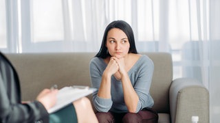 Eine Frau sitzt bei der Psychotherapeutin auf dem Sofa