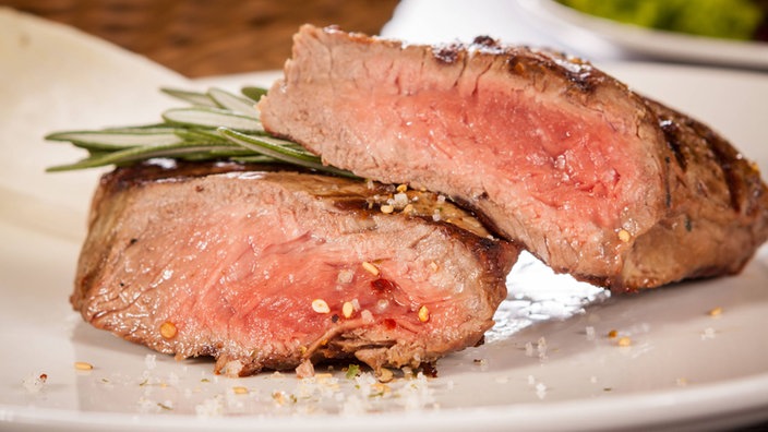 Medium gebratenes Rindersteak mit Pfeffer und Rosmarin aufgeschnitten auf einem Teller