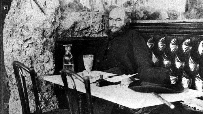 Der Schriftsteller Paul Verlaine sitzt in einem Restaurant in Paris.