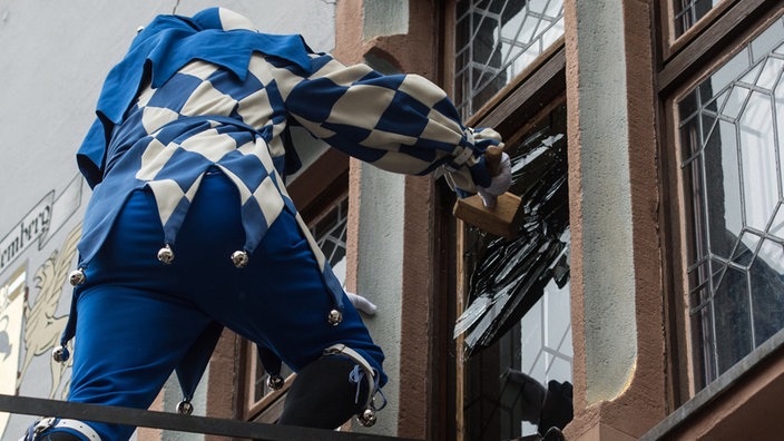 Ein verkleideter Fasnachts-Narr macht sich an der Scheibe des Rathaus zu schaffen