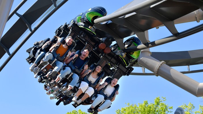 Menschen auf der Achterbahn mit freihängenden Füßen