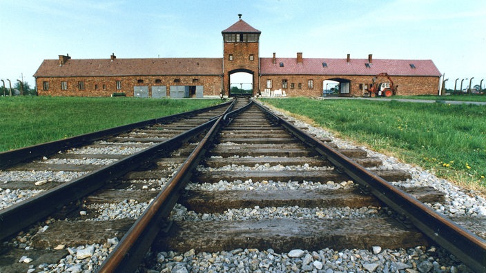 Bahngleise führen auf eine Toreinfahrt im Hintergrund zu.