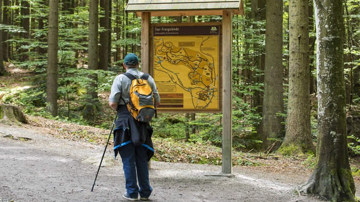 Wanderer vor Hinweistafel