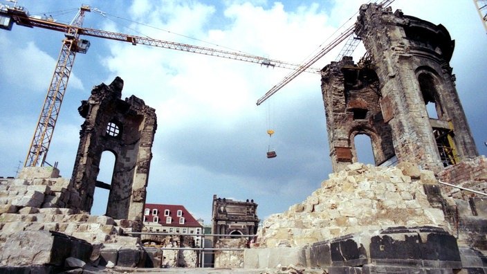 Blick auf die Trümmer der Frauenkirche. Rechts und links stehen Kräne.