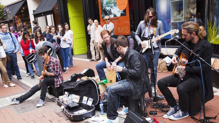 Eine junge Band sitzt auf der Straße und spielt auf ihren Instrumenten