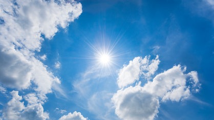 Blauer Himmel mit wenigen Wolken und Sonne.