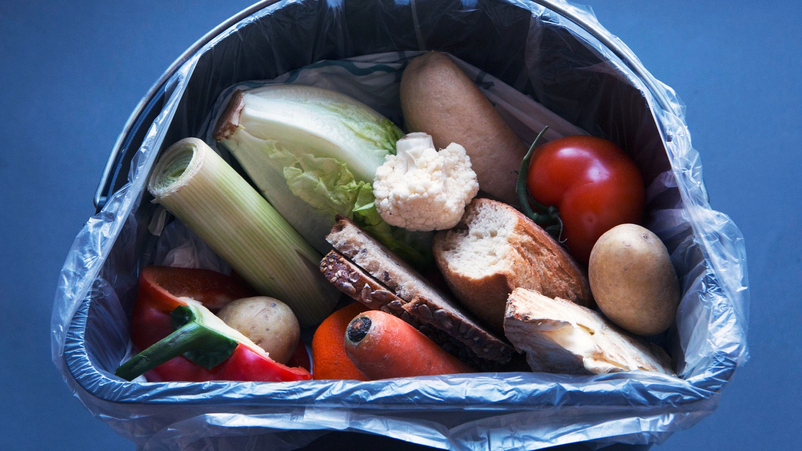 Zwei Packungen Fleisch, eine Dose Margarine und andere Lebensmittel in einer Mülltonne