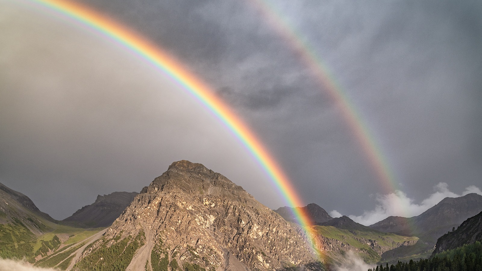 Zwei Regenbögen über einem Berg.