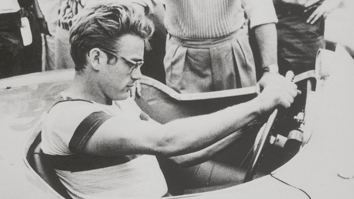 James Dean, in einem Rennwagen sitzend